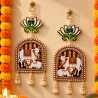 Welcome prosperity, positivity, and traditional elegance into your living space with our handcrafted Shubh Labh Kamdhenu Cow Door Hanging Set. Artisans crafted this hanging piece to elevate your home entrance, temple area, or festive setup by combining sacred symbolism with exquisite detail. At the top of each piece, a polished lotus motif displays the auspicious "Shubh" (Goodness) and "Labh" (Benefit) lettering to invite luck and wealth into your household. The centerpiece showcases detailed Kamdhenu cow and calf figures inside an arched frame lined with lustrous faux pearls. Beaded pearl tassels hang from the bottom to add graceful movement and classic charm. Built with durable materials, this versatile wall decor set shines during Diwali celebrations, housewarming ceremonies (Griha Pravesh), weddings, or everyday spiritual displays. Hang it on main doors, gallery walls, or pooja room entryways to instantly create a warm, inviting, and sacred atmosphere.