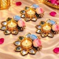 Set of four gold floral mirror tealight candle holders with blue and pink flowers on a silk surface.