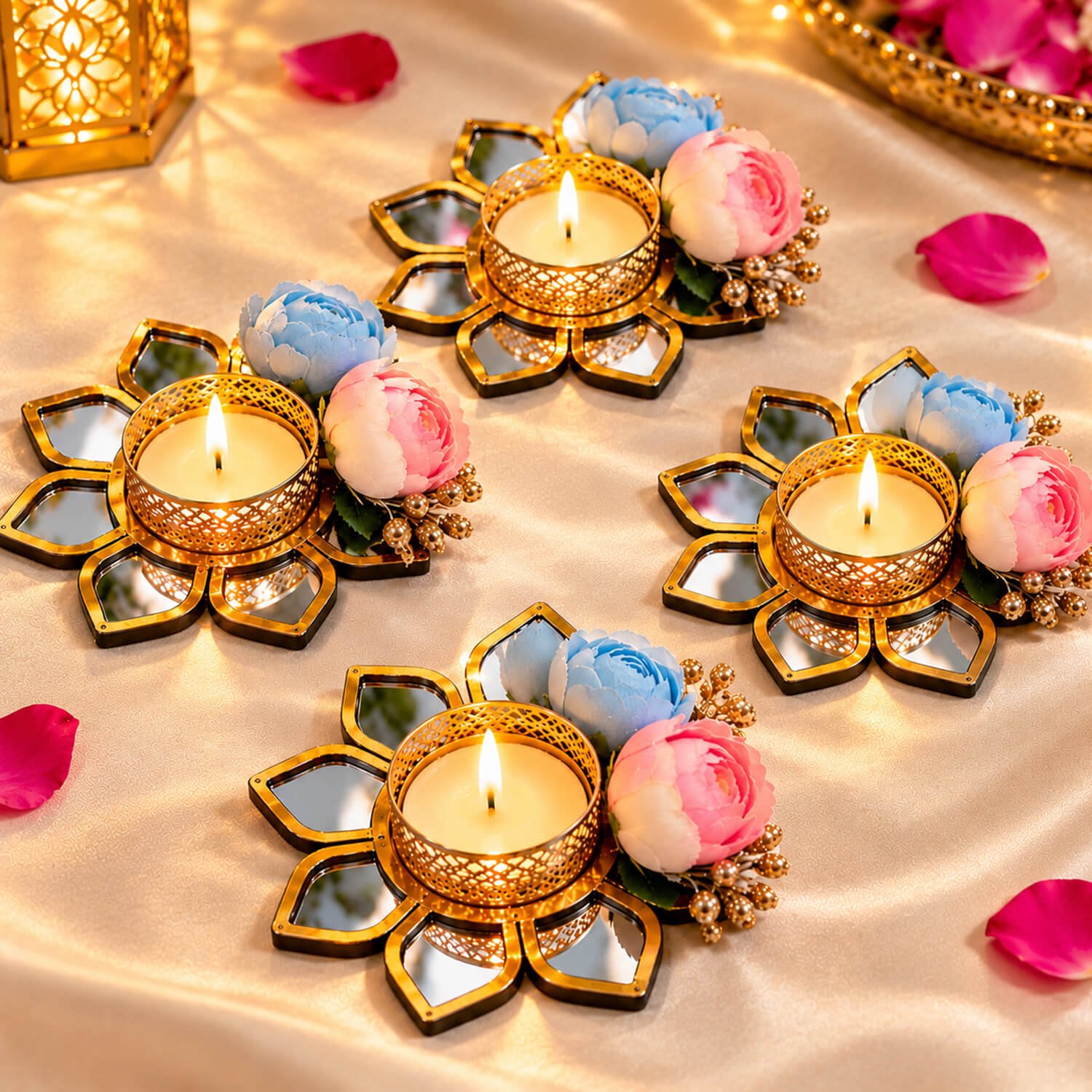 Set of four gold floral mirror tealight candle holders with blue and pink flowers on a silk surface.